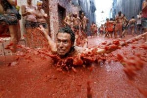 Un joven nada entre los 110.000 kilos de tomate que se han lazado hoy por las calles de la pequeña localidad española de Buñol (Valencia), con motivo de la fiesta de la Tomatina